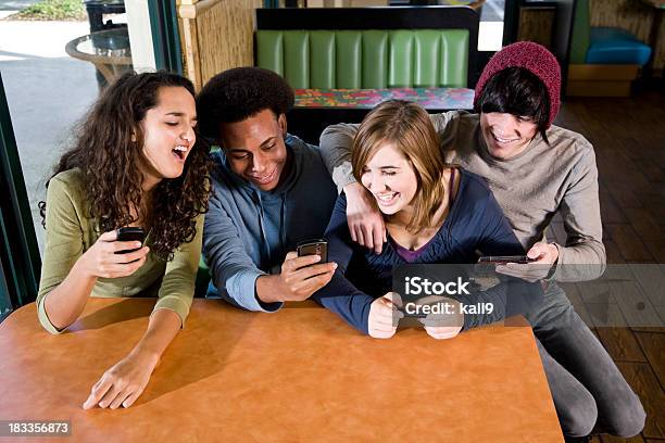 Multietnico Adolescenti In Diner Inviare Sms Sui Cellulari - Fotografie stock e altre immagini di Adolescente