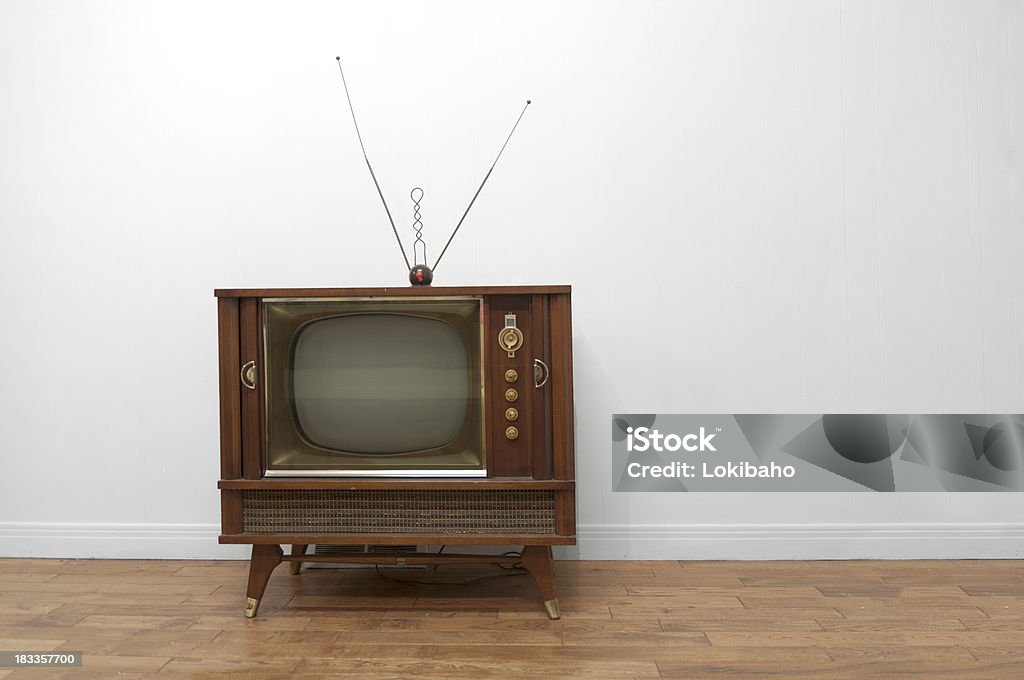 Television 1950s Console Television with rabbit ear antenna on a wood floor and white wall Television Set Stock Photo