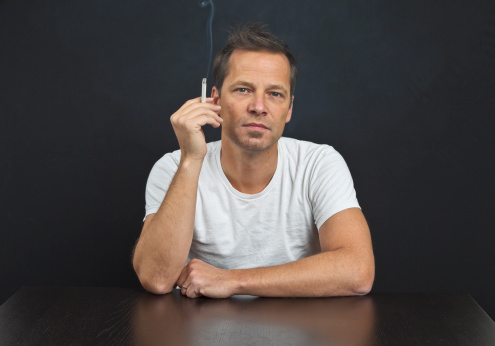 Mid-age man smoking on black background Studio Shot