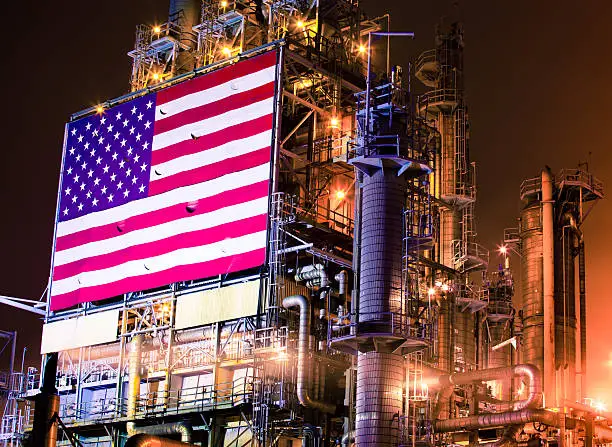 Night photograph of a huge industrial chemical plant and oil refinery installation in Southern California is adorned with a massive American flag.