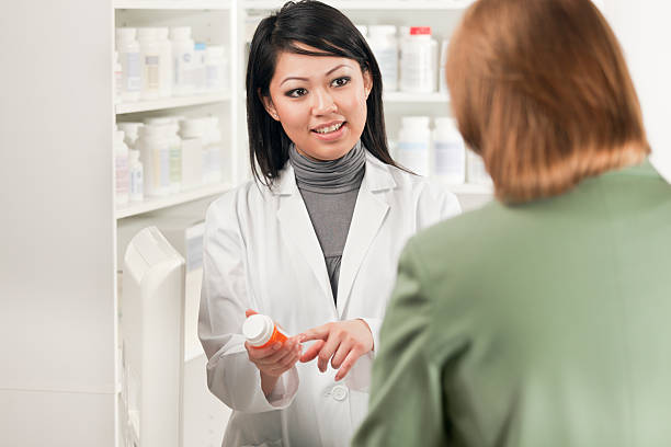 薬剤師アジア人の女性が顧客に販売している医薬品の保管 - pharmacy pharmacist smiling pill ストックフォトと画像