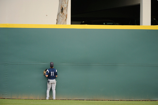 A baseball player can only watch as the ball clears the wall for a home run.