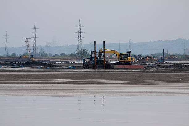 Excavators at village devastated by Mud Volcano "Location: Sidarjo-Surabaya, East Java, IndonesiaDate of photo: 5 December, 2010.The whole area visible in the Photo used to be an large village.The Sidoarjo mud flow, in the subdistrict of Porong, Sidoarjo in East Java, Indonesia is the biggest mud volcano in the world. Approximately 1 million cubic feet of mud aa equivalent to the contents of a dozen Olympic-size swimming pools aa are expelled per day.(As of Dec 2010) It is expected that the flow will continue for the next 30 years.  It has been ongoing since May 2006. See more photos like this, and related in:" mud volcano stock pictures, royalty-free photos & images