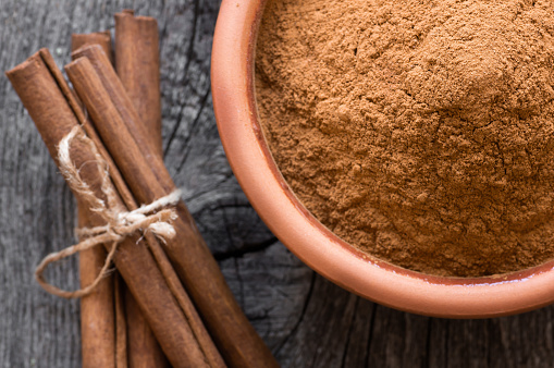 Cinnamon sticks and cinnamon powder on rustic background, healthy spice, (Cinnamomum)