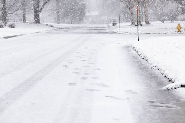 istock Footprints in Falling Snow on Residential Street 183360187