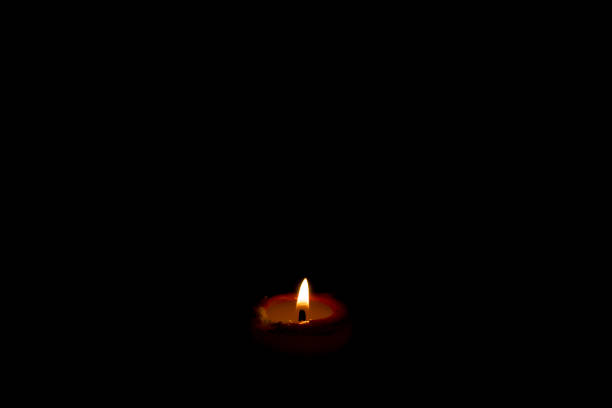 Burning red candle flame with dark horizontal background with area for copy space
