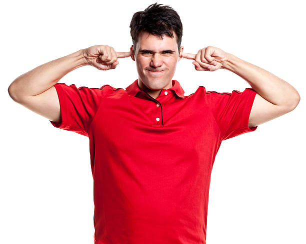 Annoyed Man With Fingers Plugging Ears Portrait of a young man on a white background. http://s3.amazonaws.com/drbimages/m/dordar.jpg hands covering ears stock pictures, royalty-free photos & images