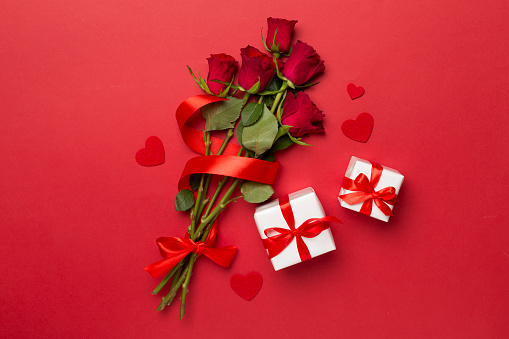 Valentines day gift boxes with red roses on color background, top view