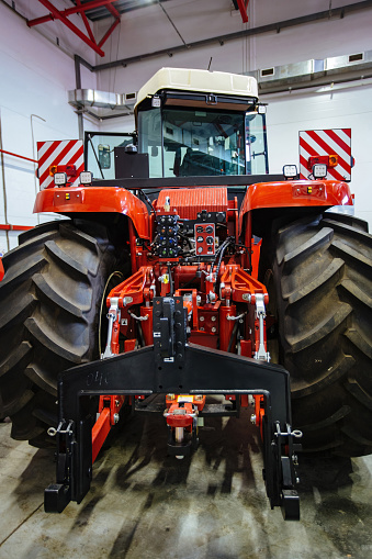 Rear view of modern agricultural tractor in hangar. Hydraulic hitch. Hydraulic lifting frame. Rear mechanism for attaching trailed equipment