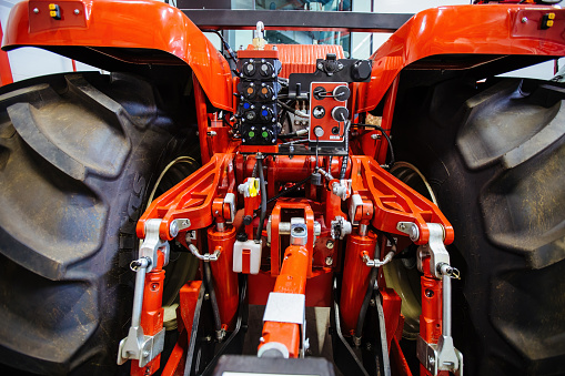 Rear view of modern agricultural tractor in hangar. Hydraulic hitch. Hydraulic lifting frame. Rear mechanism for attaching trailed equipment