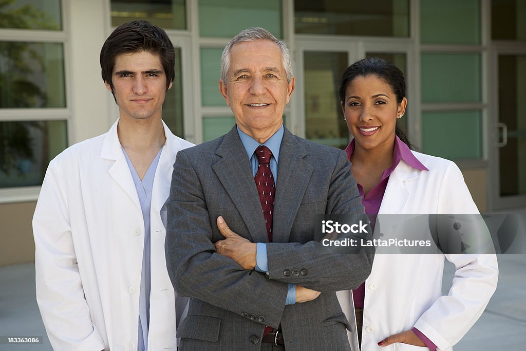 Uomo d'affari Senior con due persone che indossano giacche di laboratorio - Foto stock royalty-free di Dentista