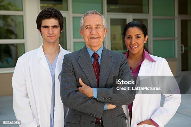 Uomo Daffari Senior Con Due Persone Che Indossano Giacche Di Laboratorio - Fotografie stock e altre immagini di Dentista