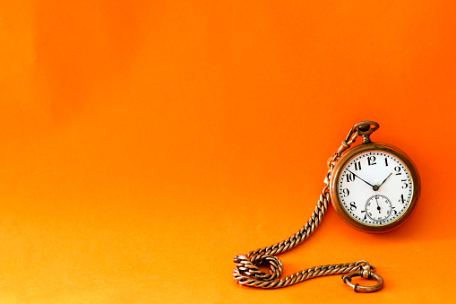 Antique clock on orange background with space for copy on the left