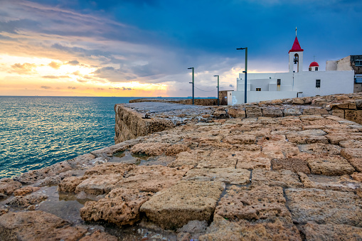 Waterfront in the Old City of Acre, Israel at sunset with St. John Baptist Church at sunset.