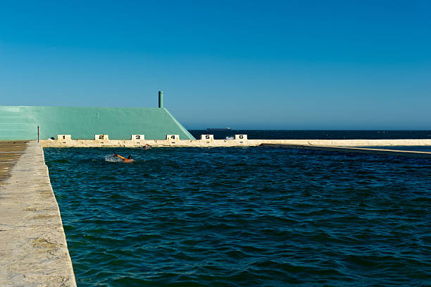 Swimmers at Newcastle Ocean Bath swimmers in Newcastle main beach ocean bath swimming pool with blue sky newcastle australia stock pictures, royalty-free photos & images