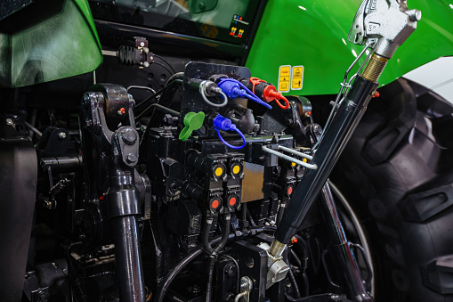 Rear view of modern agricultural tractor in hangar. Hydraulic hitch. Hydraulic lifting frame. Rear mechanism for attaching trailed equipment