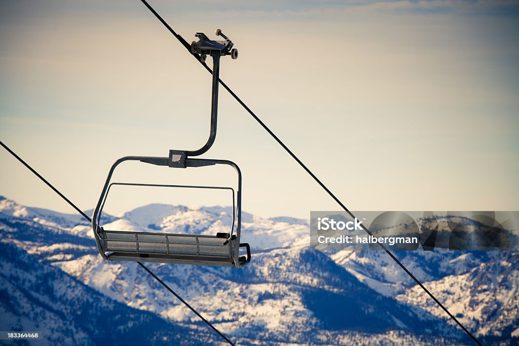 Cross-Processed Ski Lift Empty chair of a ski lift with snow-capped mountains in the background.  Cross-processed image. Lake Tahoe Stock Photo