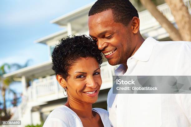 Coppia Sorridente Con La Loro Casa In Background - Fotografie stock e altre immagini di Abbigliamento casual - Abbigliamento casual, Adulto, Adulto in età matura