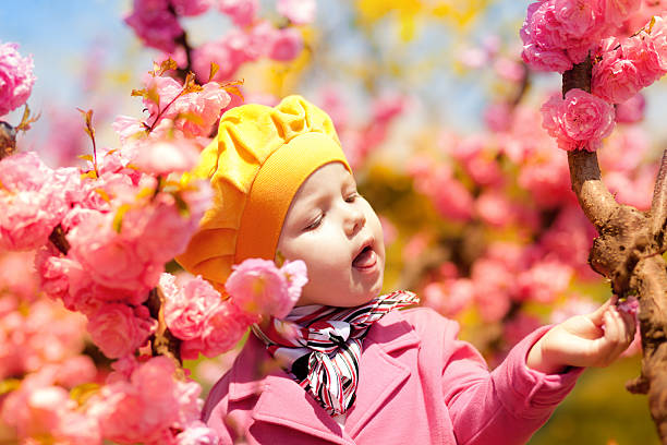 Beautiful baby girl in blooming apricot tree branches