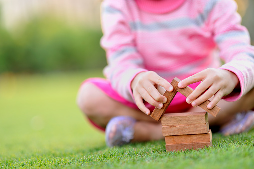 concept image of young child building house on green grass.