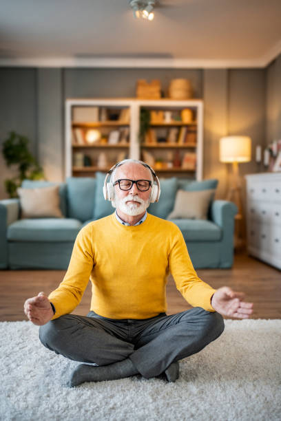 istock Elderly man, pensioner, sitting on floor practicing guided meditation at home, relaxing body and mind concept 1833659644