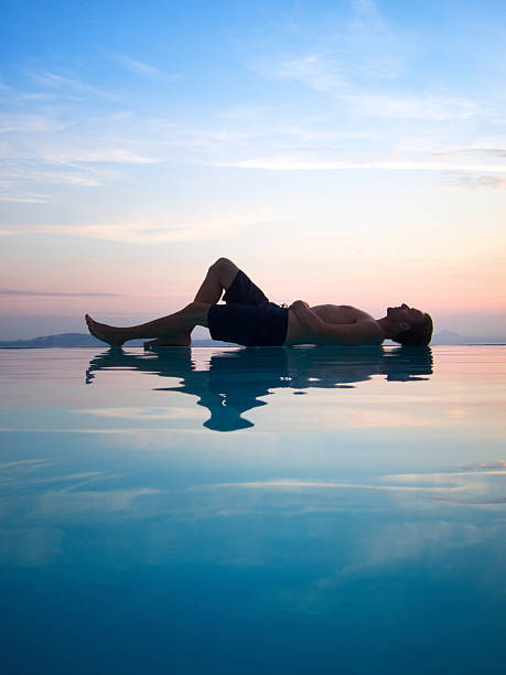 istock Man Relaxes Reflecting on Sunset Infinity Swimming Pool 183367194