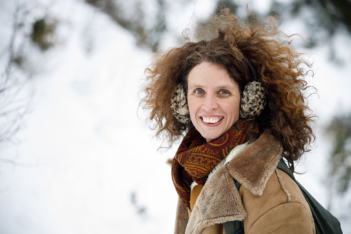 Mid Adult Woman's Portrait: Beautiful Curly Long Hair, Toothy Smile, Dressed in Vintage Mountain Style Clothes, Enjoying Snow Landscape