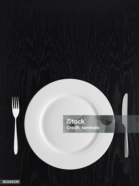 A White Plate A Knife And A Fork On A Black Table Stock Photo - Download Image Now