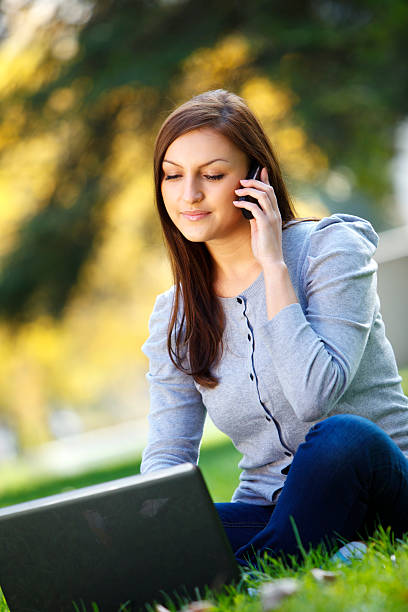 istock Beautiful young woman working on laptop and using cell phone 183369654