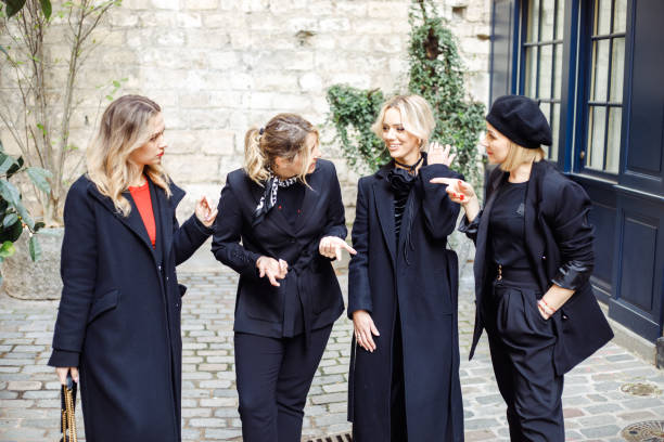 Four wonderful blondie friends discuss something interesting while walking together along streets of romantic Paris.
