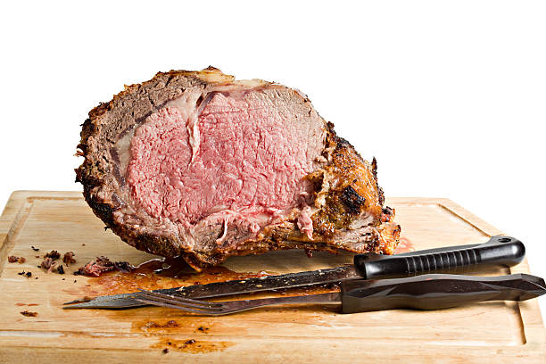 Sliced Roasted Prime Rib With Knife On Plank Sliced roasted prime rib on wooden plank isolated. roast beef photos stock pictures, royalty-free photos & images