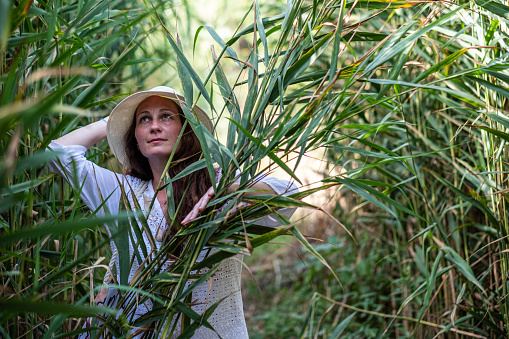 a beautiful woman peeks out from the reeds while going to the beach