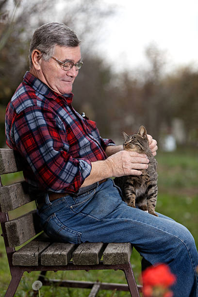 istock Senior man sitting on bench in the park with cat 183372788