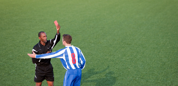 Soccer player receiving a red card from the match referee