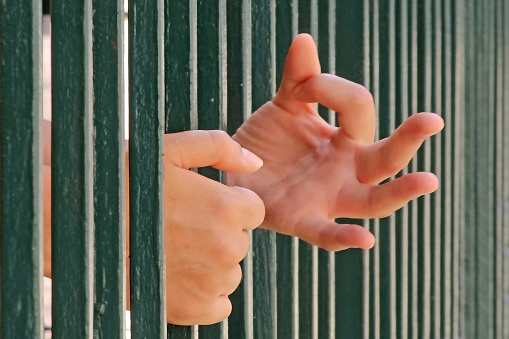 Young woman trapped behind bars