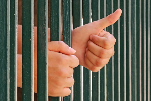 Young woman trapped behind bars