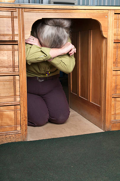 Senior woman hiding under her desk