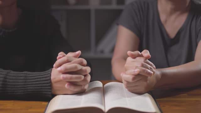 Couple praying together with bible, faith on table, indoor and connection. People, support and book for religion, study and empathy with gratitude for holy spirit