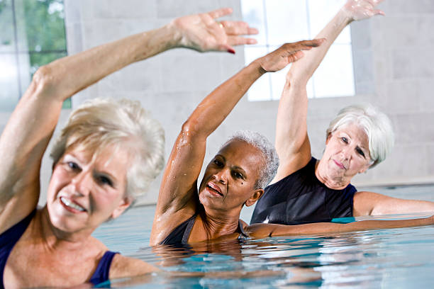 multiraciale femmes seniors dans l'eau cours d'aquagym - water aerobics swimming pool exercising sport photos et images de collection