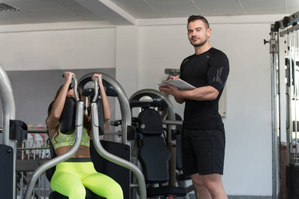 istock Woman Train Chest On Machine With Personal Trainer 1833787301