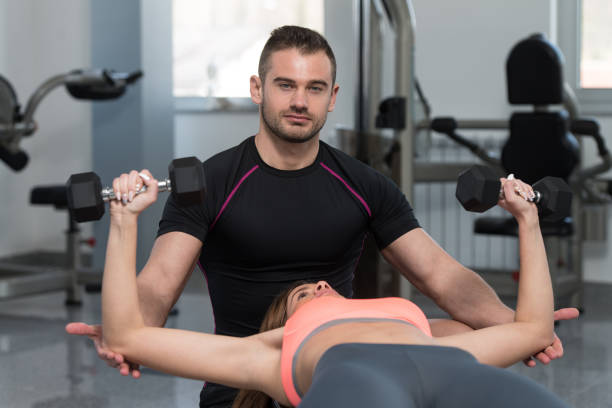 istock Gym Coach Helping Woman On Chest Exercise 1833787413