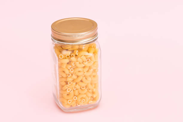 istock Uncooked Chifferi Rigati Pasta in Glass Jar on Pink Background 1833792237