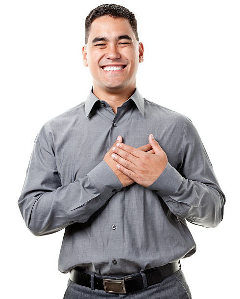 grinning felice giovane uomo con le mani sul cuore - hand on heart immagine foto e immagini stock
