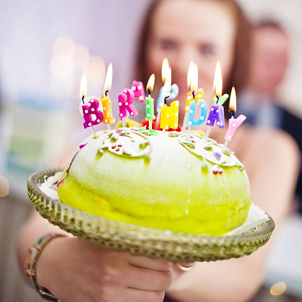 Colorful festive cake covered with whipped cream and topped with meringue drops and colorful birthday candles. Vibrant dessert for  15th anniversary celebration