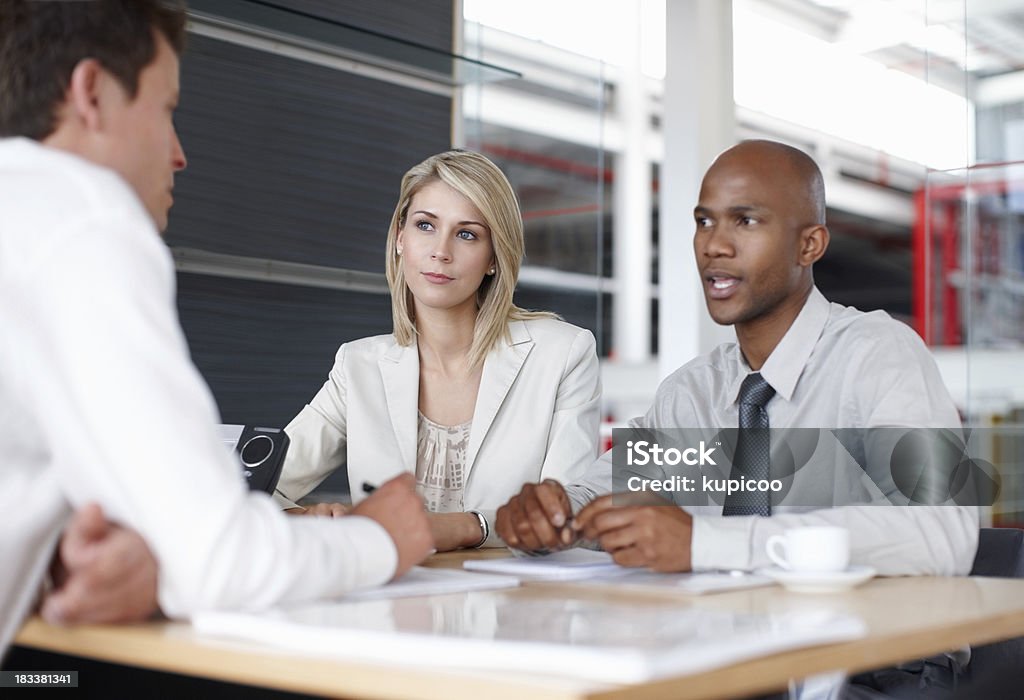 Team of three discussing business plans in meeting Portrait of a team of three discussing business plans in meeting Business Stock Photo