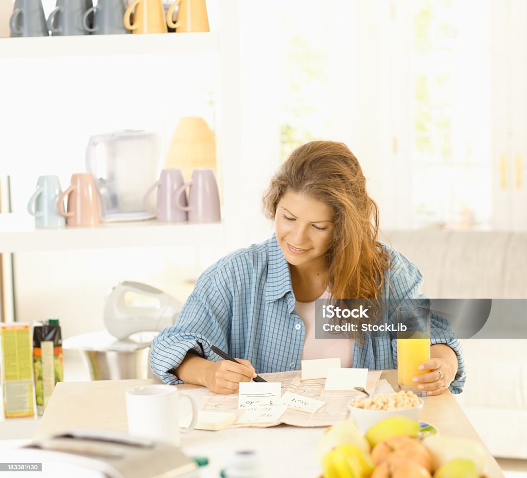 Młoda kobieta Pisanie notatek w kuchni - Zbiór zdjęć royalty-free (20-24 lata)