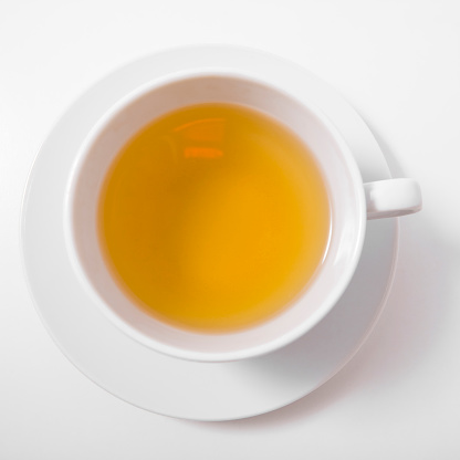 Herbal tea with cinnamon sticks on white wooden background.