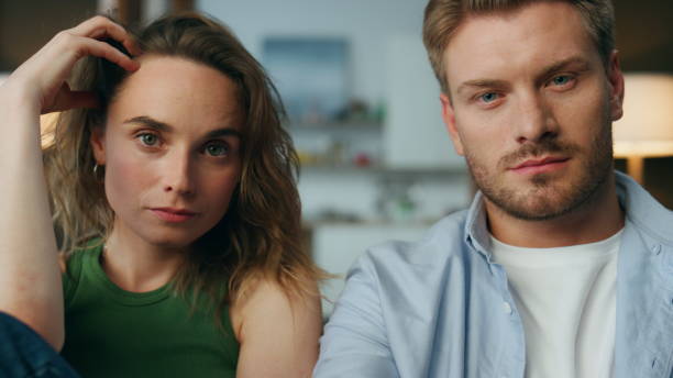 istock Focused pair staring tv show at home closeup. Man hand holding remote controller 1833825521