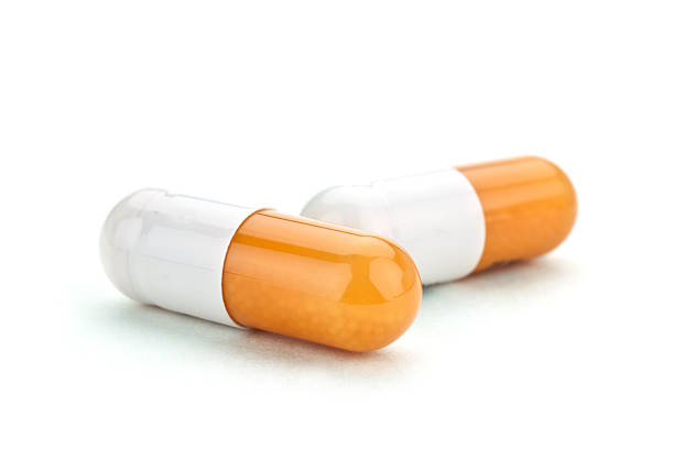 Pills Two orange and white capsules filled with beads of medication. capsule medicine stock pictures, royalty-free photos & images