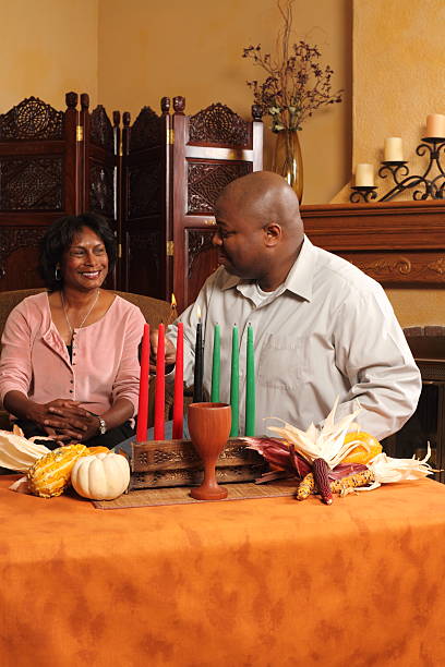 Man glances at wife after lighting first Kwanzaa candle.